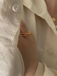 Close-up of a layered gold beaded crossover ring worn by a model in a lifestyle setting