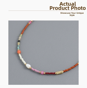 Détail d'un collier bohème avec perles colorées, perle baroque et tube en métal doré