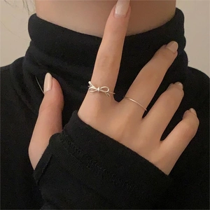 Detailed close-up of S925 sterling silver bow ring and minimalist band on model hand