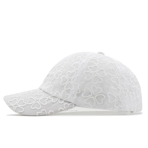 Close-up of white lace baseball cap featuring intricate heart-shaped clover embroidery