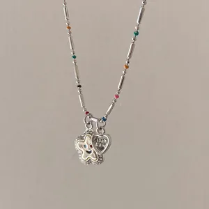 Close-up of beaded necklace with silver tubes, colorful beads, and star heart pendants