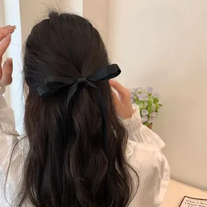 Detail of elegant black satin bow hair clip with long ribbons on a half-up hairstyle