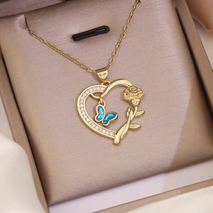 Macro shot of 18K gold heart pendant with blue opal butterfly and rose in gift box