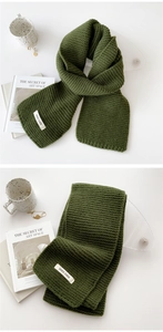 Close-up of dark green knitted scarf texture and rectangular white fabric brand label