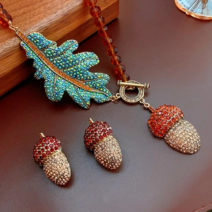 Vintage jewelry set featuring leaf and acorn pendants with vibrant crystals on a gold chain