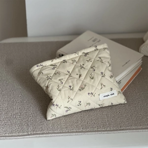 Close-up of diamond quilted corduroy makeup bag with floral print and a woven label