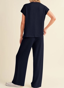Rear view of navy blue ribbed knit set showing vertical texture of top and wide-leg trousers