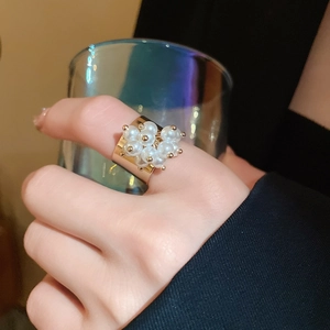 Close-up of golden wide-band open ring with pearl flower cluster on hand