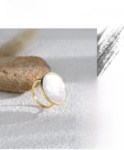 Detailed view of vintage gold ring with oval mother of pearl on textured white fabric