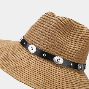 Close-up of straw sun hat featuring black leather band with silver ethnic metal studs