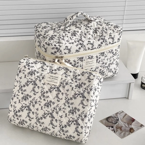 Quilted makeup bag set with black floral pattern on white fabric and fabric labels