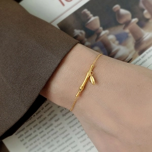 Elegant 18k gold bamboo joint bracelet with leaf charm on a woman's wrist