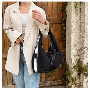 Detail of black nylon hobo bag with a striped wide strap and a small detachable pouch