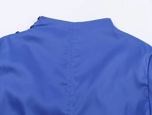 Makro-Detail von blauem Faltenhemd-Kragen mit schwarzem Knopf und hinterer Nahtführung