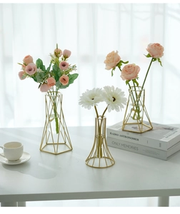 Close-up of geometric gold metal vases with glass tubes and pink roses for home decor