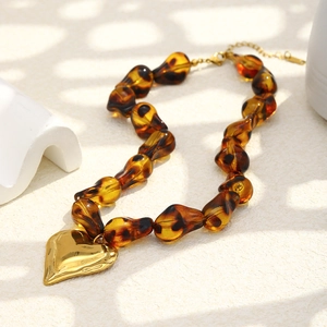 Leopard print beaded necklace with a large gold mirror heart pendant on stone background