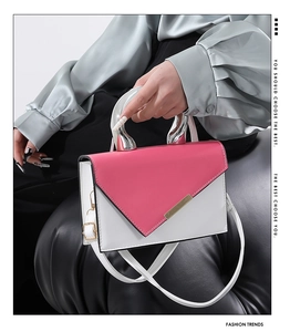 Detail of a pink and white contrast crossbody bag with a sleek chrome metal handle