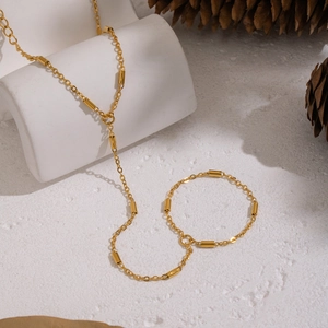 Ensemble collier et bracelet en acier inoxydable doré sur fond de pierre décorative