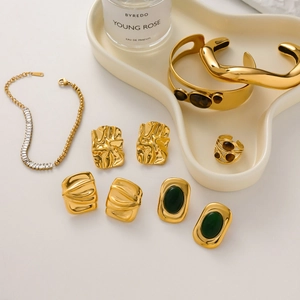 Detail of tiger eye stone jewelry set with gold textured earrings and bangle on a tray