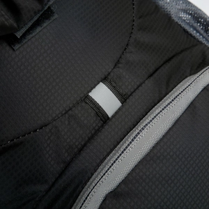 Macro detail of tear-resistant nylon fabric with reflective loop and grey zipper for men's bag