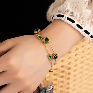 Double-layered 18K gold plated bracelet with green heart gemstones on a female wrist