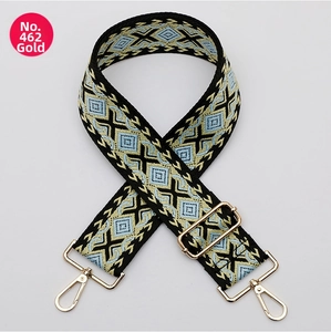 Close-up of geometric embroidered bag strap with gold metal hooks and adjustable buckle