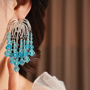 Close-up of sky blue faceted beads tassel earrings on a model with shimmering silver finish