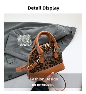 Detail view of leopard print shell bag with double gold zippers and brown leather trim
