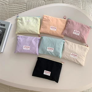 Flat lay of small nylon makeup bags in seven pastel colors with Sozakka logo