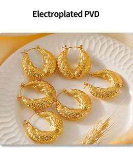 Detailed view of three pairs of vintage gold feather earrings on white ceramic