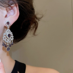 Close-up of vintage silver drop earrings with purple pear-cut crystals on a model