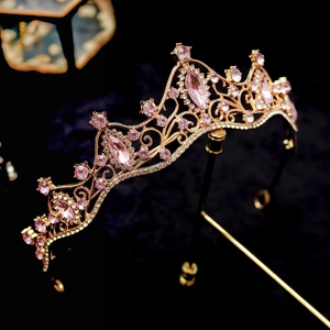 Detail view of rose gold crown with pink crystals on a black velvet background