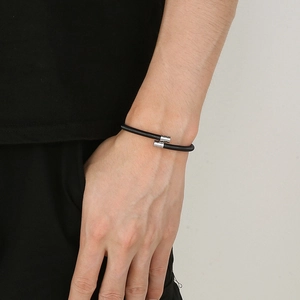 Close-up of black braided mesh bracelet with silver cylindrical magnetic clasps on wrist