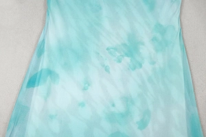 Detail of mint green and white tie-dye chiffon fabric with elegant draped texture
