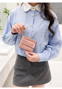 Detail of pink PU leather coin purse with gold keychain held by a hand in bright lighting