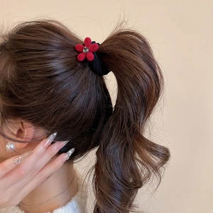 Détail de l'élastique fleur rouge floquée avec strass sur une queue de cheval haute
