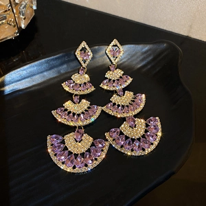 Macro detail of fan-shaped earrings with purple crystal teardrops and sparkling rhinestones