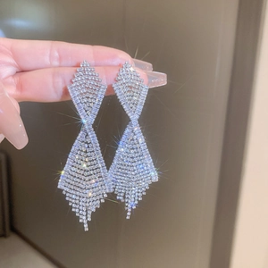 Macro shot of silver diamond-encrusted tassel earrings with sparkling starburst effect