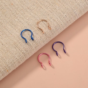 Detail of four colorful U-shaped faux nose rings in blue, rose gold, purple, and magenta