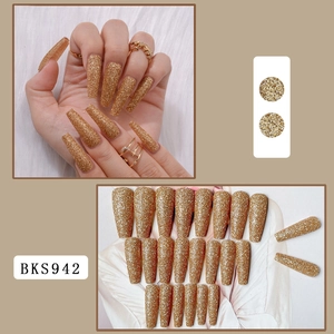 Detail of long coffin-shaped gold glitter press-on nails with shimmering textured finish