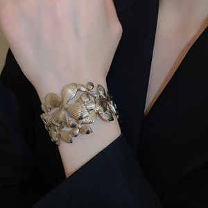 Détail macro du bracelet argenté ajouré à motif floral avec texture brossée