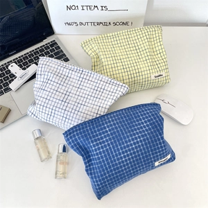 Close-up of three checkered fabric cosmetic bags in blue and yellow colors on a white desk