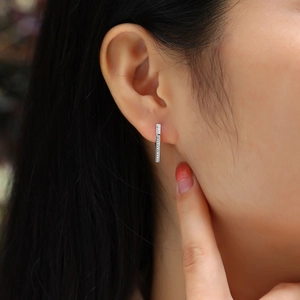 Close-up of minimalist silver hoop earrings with double row moissanite on a model