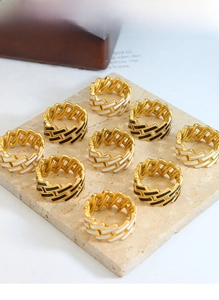 Close-up of woven gold titanium steel rings with black and white enamel on stone stand