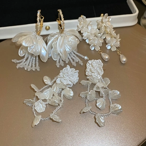 Detailed view of floral pearl earrings with elegant tassels and white resin petals