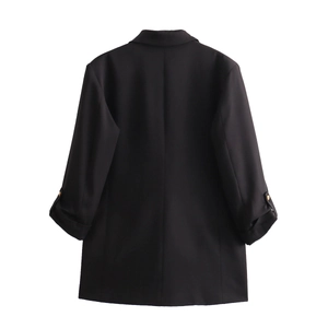Detail view of the back tailoring of a black oversized blazer with gold sleeve buttons