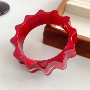Detailed macro shot of red resin gear-shaped bangle on a brown velvet jewelry tray