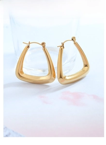 Macro detail of geometric triangle hoop earrings with 18k gold plating and polished finish