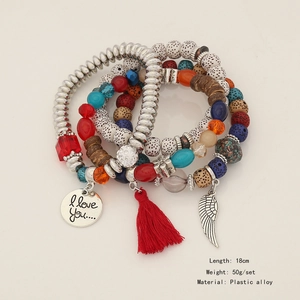 Macro shot of multi-layer beaded bracelet with red tassels and silver wing charms