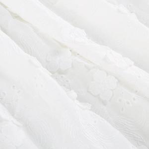 Close-up of white off-shoulder dress fabric featuring 3D floral embroidery and texture